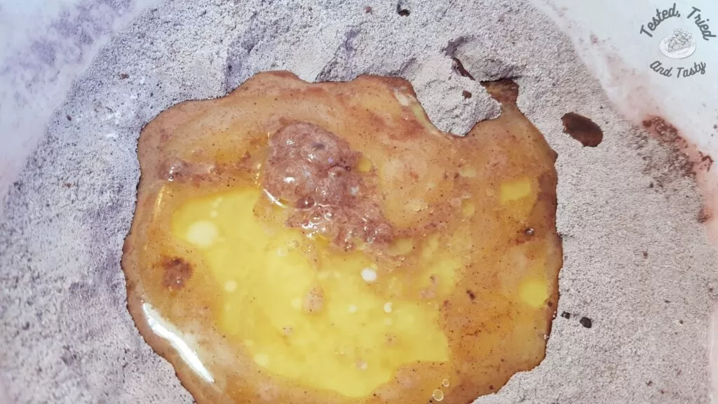 Liquid ingredients added to dry ingredients in a white bowl.