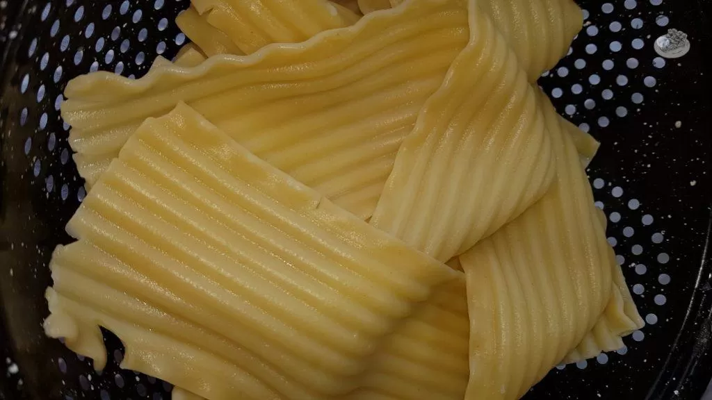 Lasagna noodles in a black strainer.