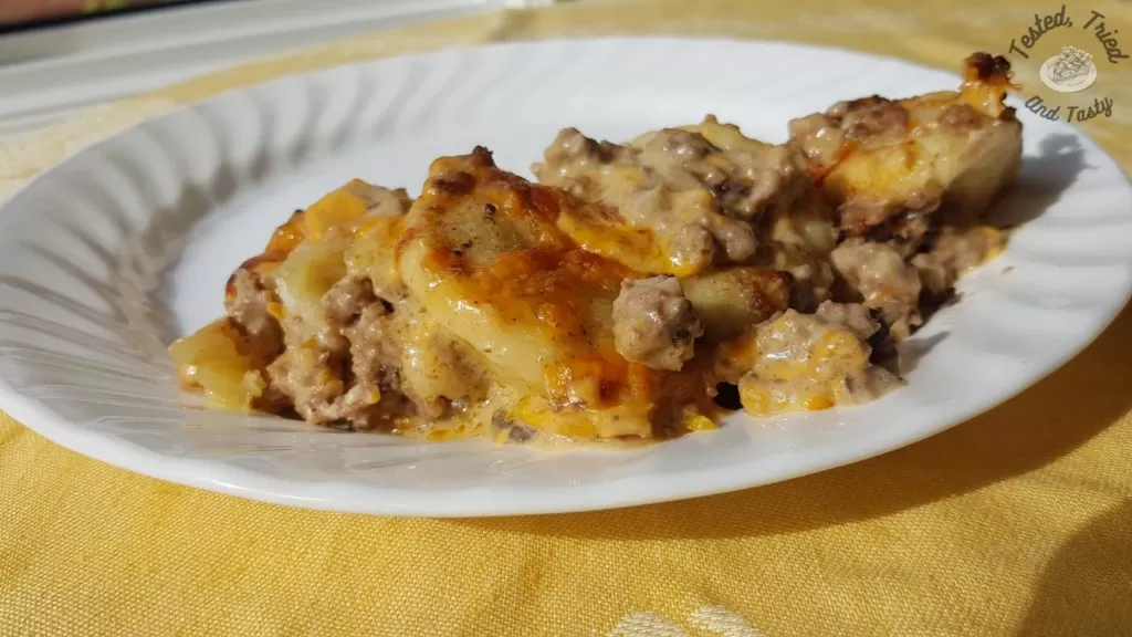 Delicious Perogy Casserole on a white plate on a yellow tablecloth.