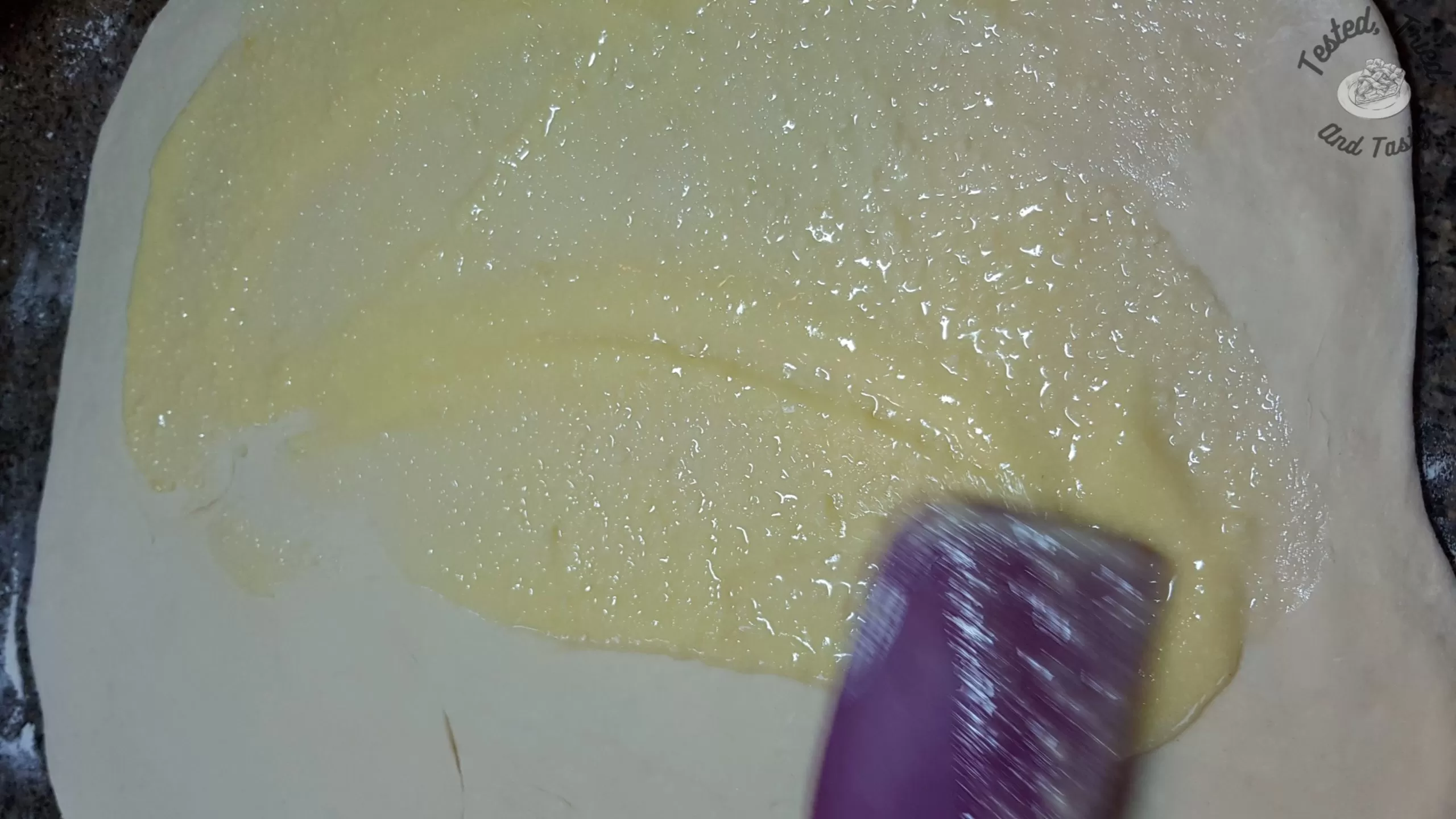 spreading melted butter, garlic, and parmesan on rolled out dough