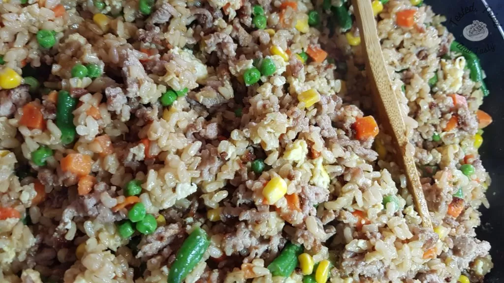 Easy pork fried rice in a saucepan with a wooden spoon