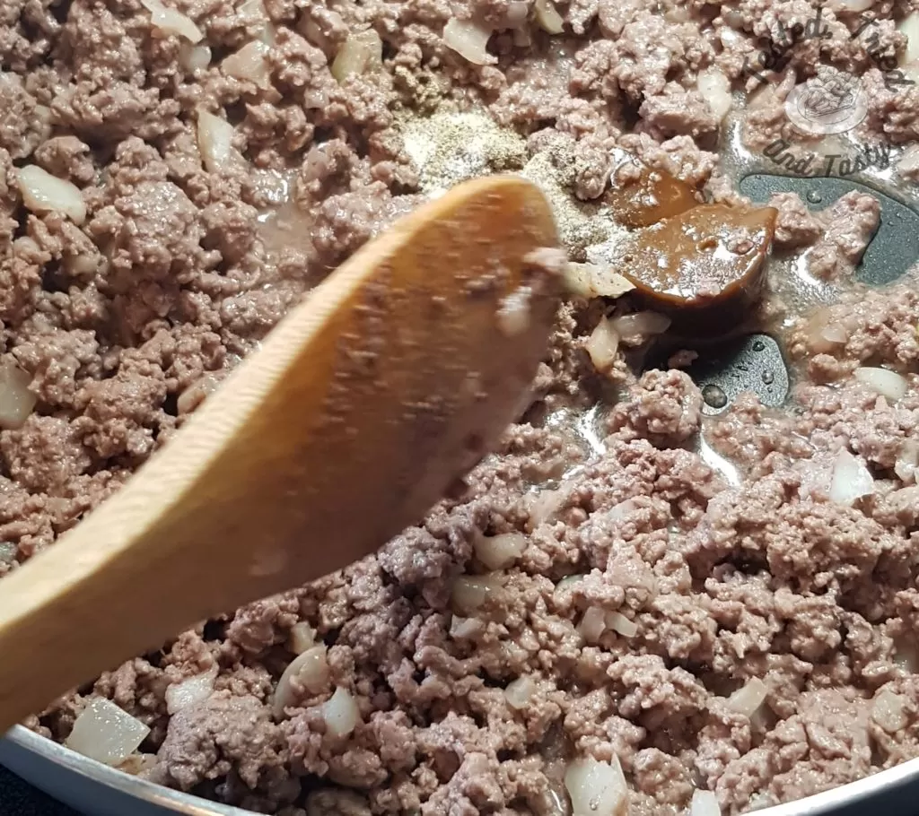 cooking ground beef and onions in a frying pan.