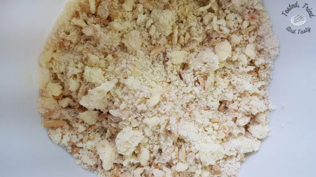 Shortbread crust with chopped toasted almonds in a white bowl.