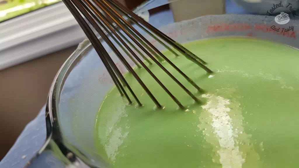 PIstachio pudding being mixed in a glass measuring cup.