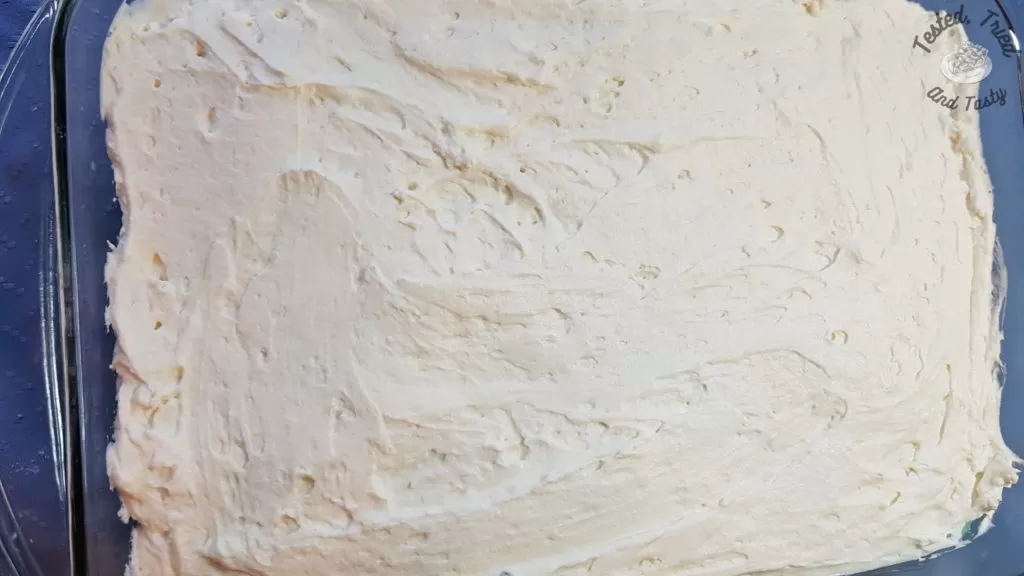 Whipped cream spread on the top of the pistachio dessert.