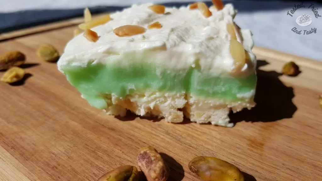 Pistachio pudding dessert on a wooden cutting board with pistachios.