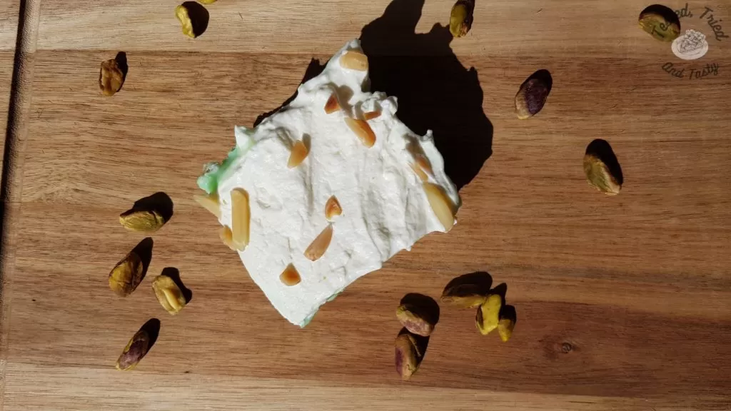 PIstachio pudding dessert on a wooden cutting board with pistachios.