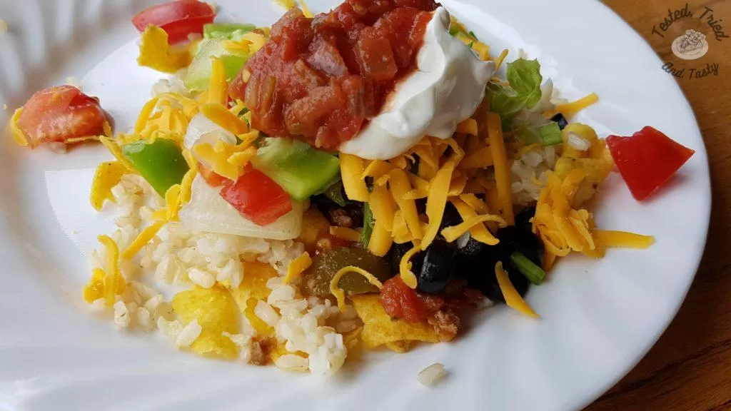 Chili stacker aka haystack on a white plate on a wooden table.