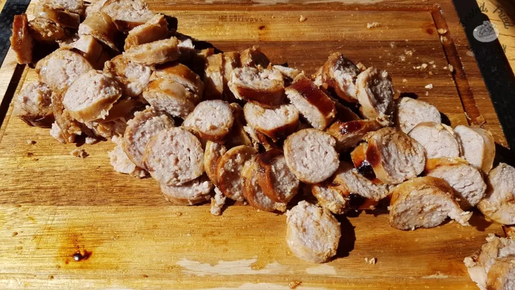 Sliced garlic sausage on a wooden cutting board.