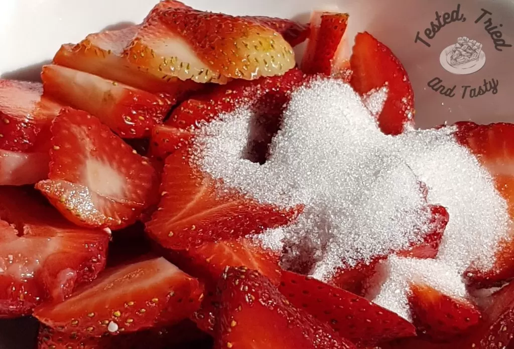 Sliced strawberries with granulated sugar.