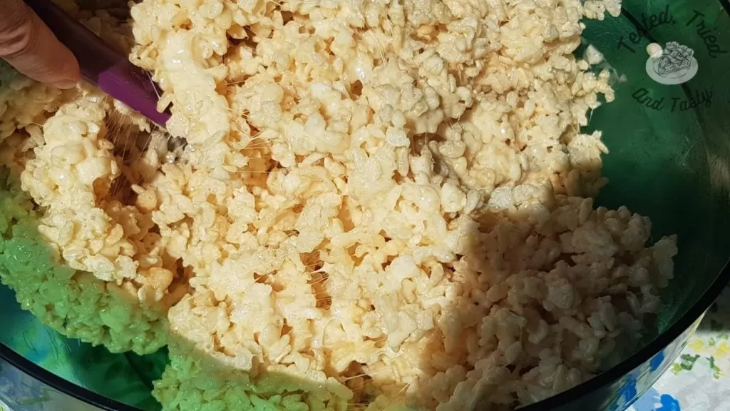Rice Krispies treat recipe in a green bowl with a purple spatula.