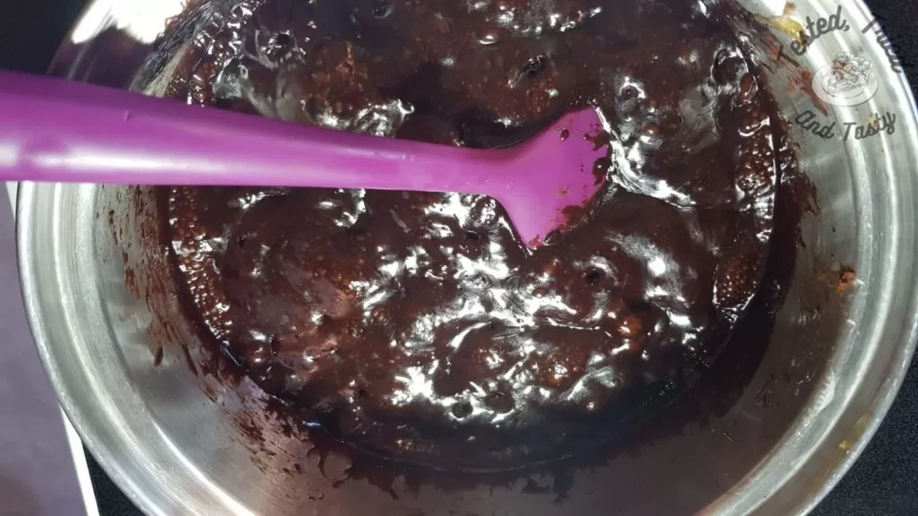 Chocolate candy syrup for puffed wheat squares in a saucepan.