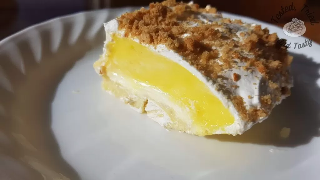 Lemon lush pudding dessert on a white plate on a wooden table.