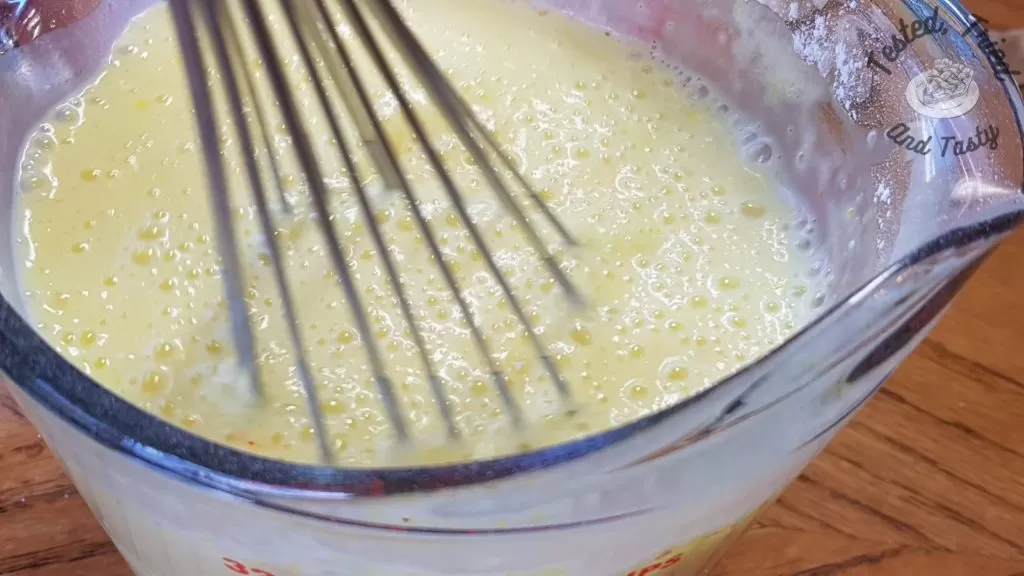 Lemon pudding being mixed in a glass measuring cup.