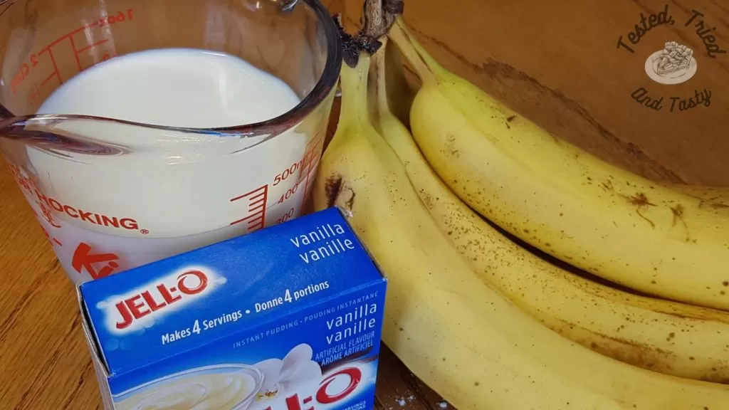 Bananas, Instant vanilla pudding and milk on a wooden table.
