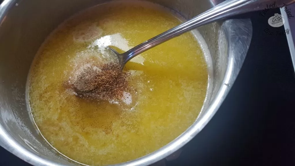 Adding spices to melted butter in a small saucepan.