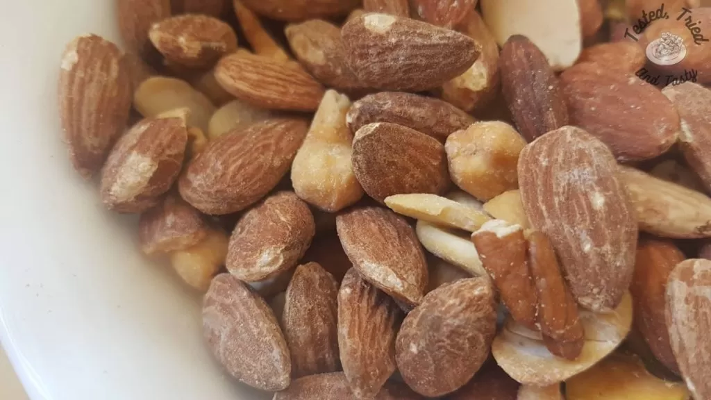 Mixed salted nuts in a white bowl.