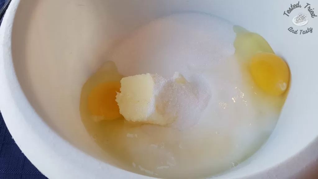 Butter, sugar, eggs and buttermilk in a white bowl.
