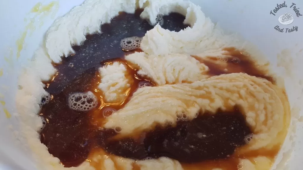 Hot coffee added to the butter/sugar mixture in a white bowl.