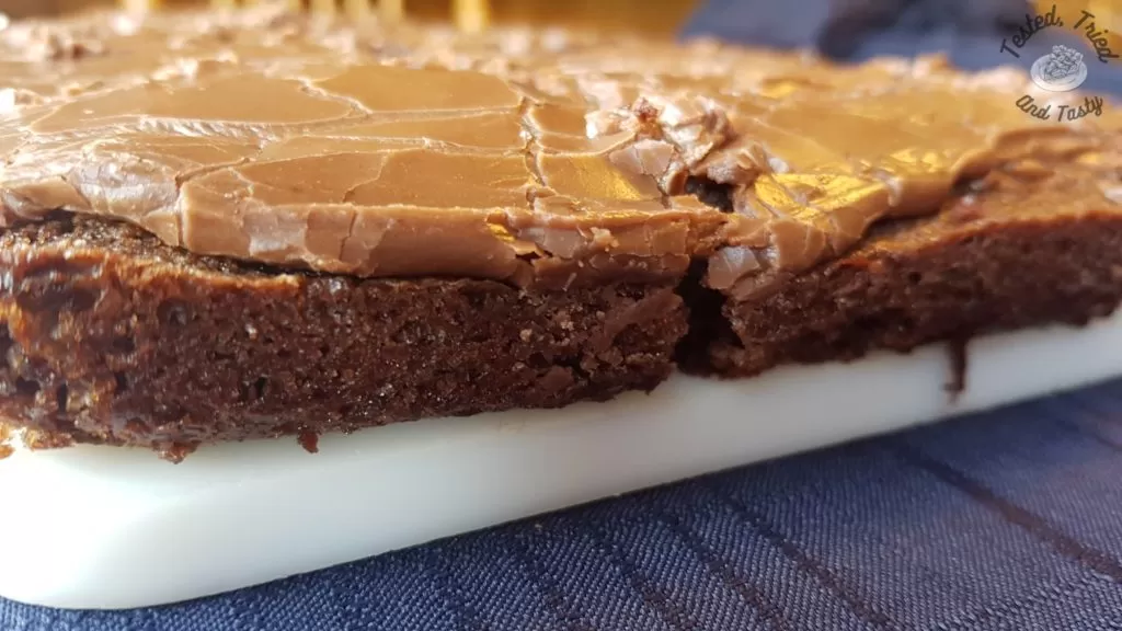 Fudgy Texas Brownies on a white cutting board on a blue tablecloth.