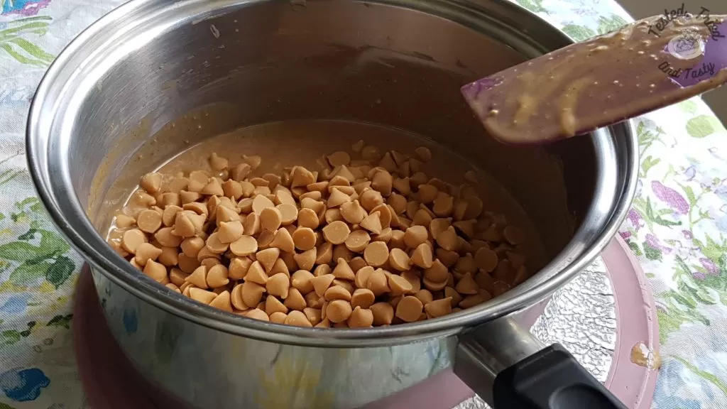 Butterscotch chips added to melted butter and peanut butter in a medium saucepan.