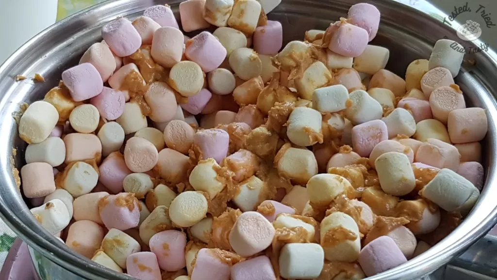 Miniature colored marshmallows added to butterscotch mixture in a medium saucepan.