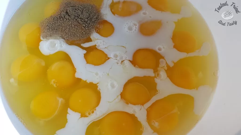 Eggs, cream and pepper in a white bowl.