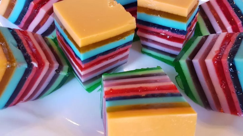 Layered Rainbow Jello on a white plate.