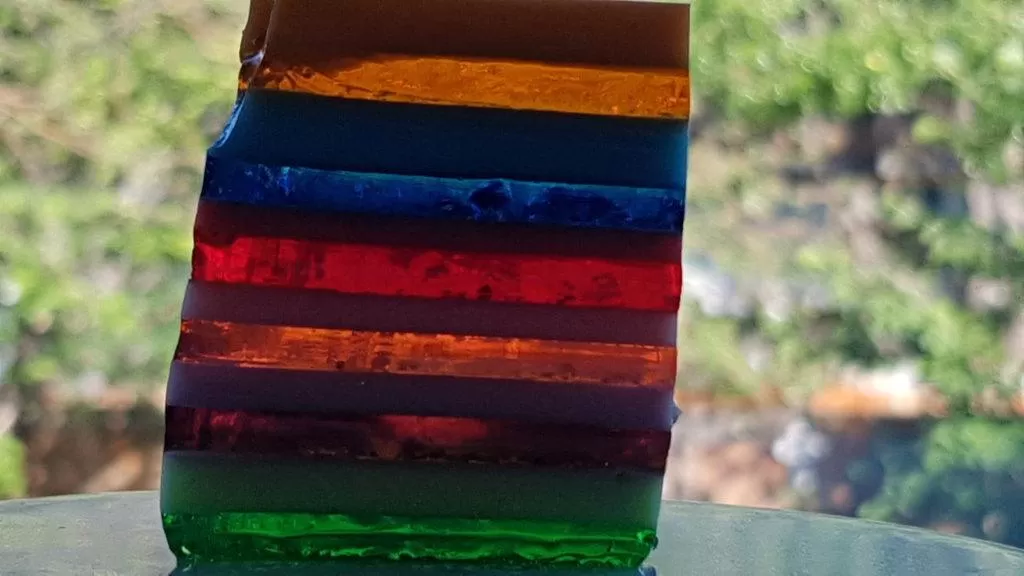Layered Rainbow Jello on a white plate.