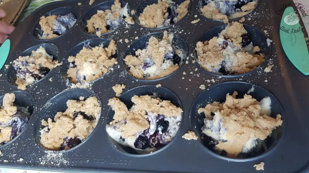 Blueberry muffin batter in a muffin tin.
