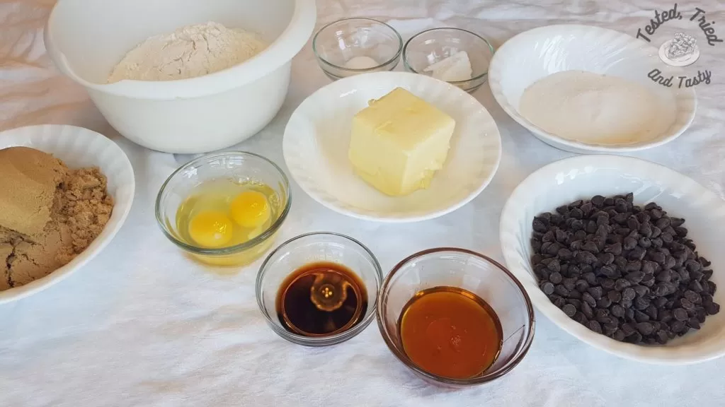 Ingredients for chocolate chip cookies on a white tablecloth.