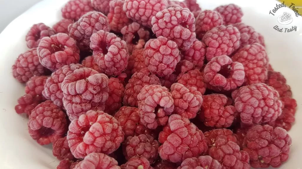 Frozen raspberries in a white bowl.