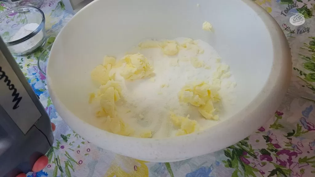 Sugar and butter being creamed together in a white plastic bowl.