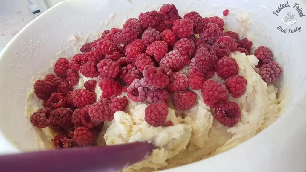 Raspberries mixed into batter for raspberry white chocolate muffins.