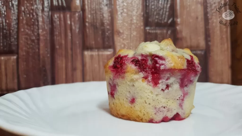 Raspberry White Chocolate muffin on a white plate.