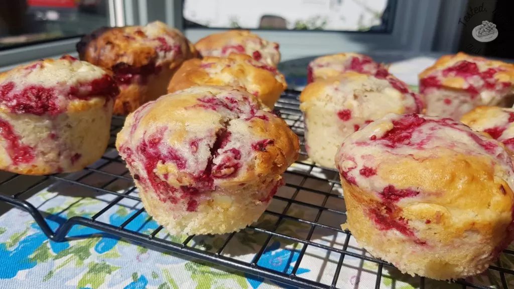 Raspberry white chocolate muffins on a wire cooling rack.