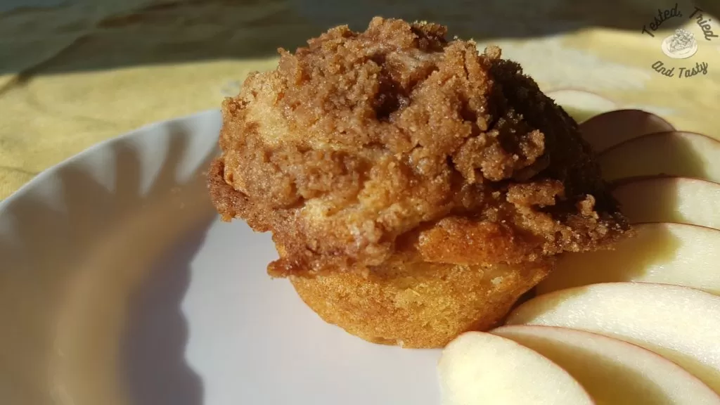 Close up of apple streusel muffin on a white plate.