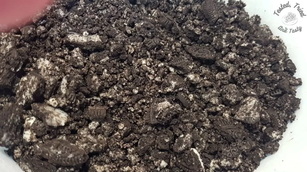 Crushed oreo cookies in a large bowl.