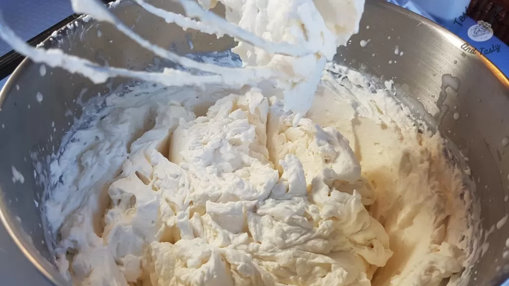 Sweetened whipped cream in a mixer bowl.