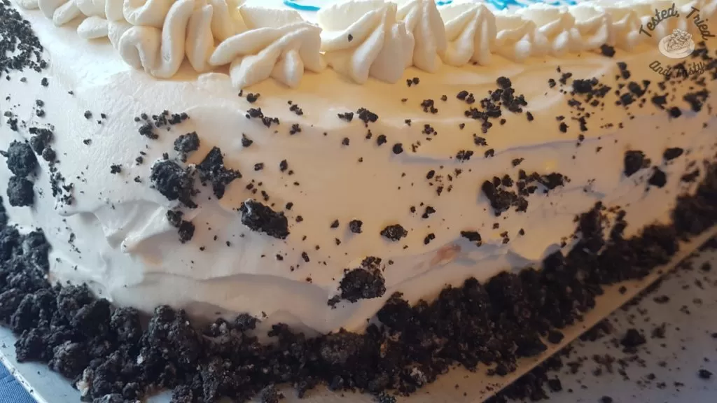 Side view of crushed oreos on the whipping cream.