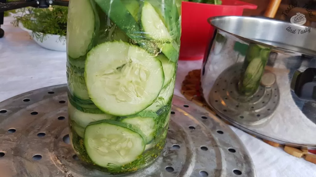 Brine added to the quart jar with garlic, dill heads, and sliced cucumbers.