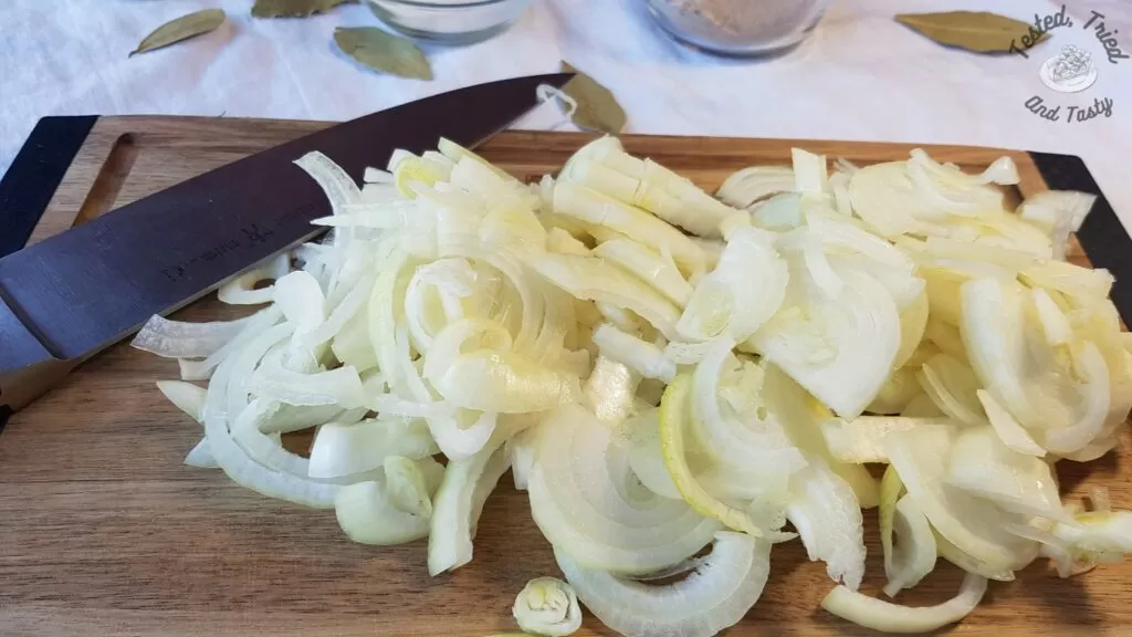 Sliced onions on a wooden cutting board.