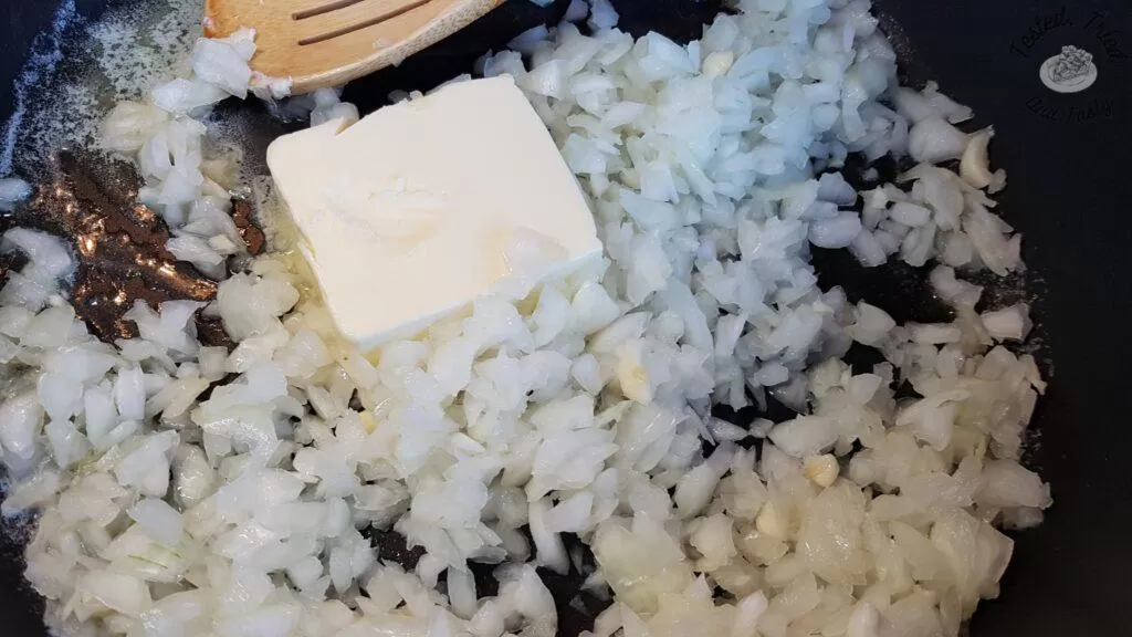 Melted butter, onions and garlic being sauteed in a large saucepan.