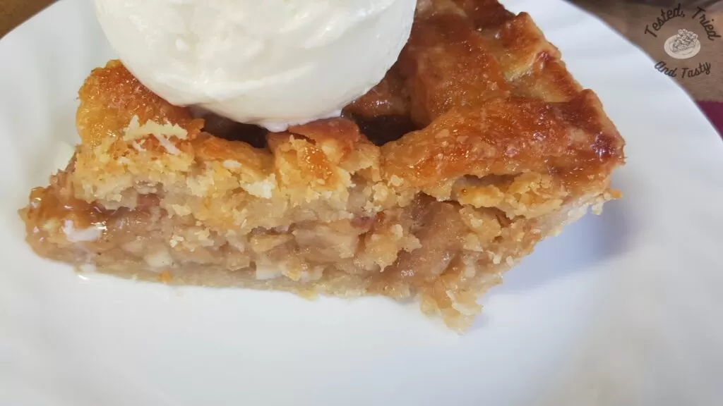 Slice of caramel apple pie on a white plate.