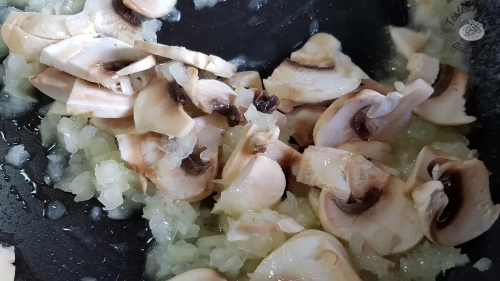 Mushrooms being sauteed in a large saucepan.