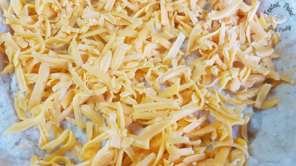 Grated cheddar cheese placed on pie crust.