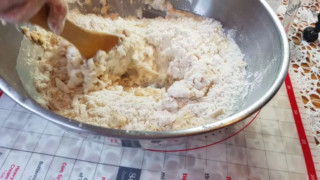 Mixing wet ingredients into the dry ingredients by hand.