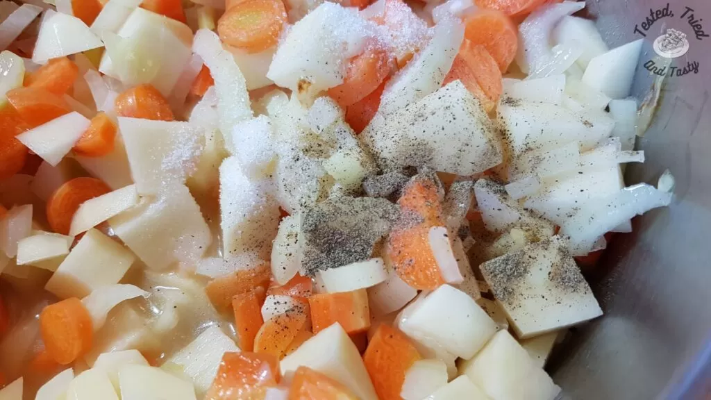 Salt and pepper added to the carrots, potatoes, onions and celery in the pan.
