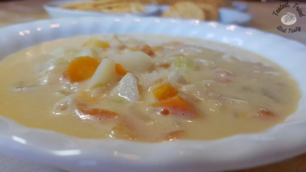 Fish Chowder in a white bowl with a plate of crackers behind it.