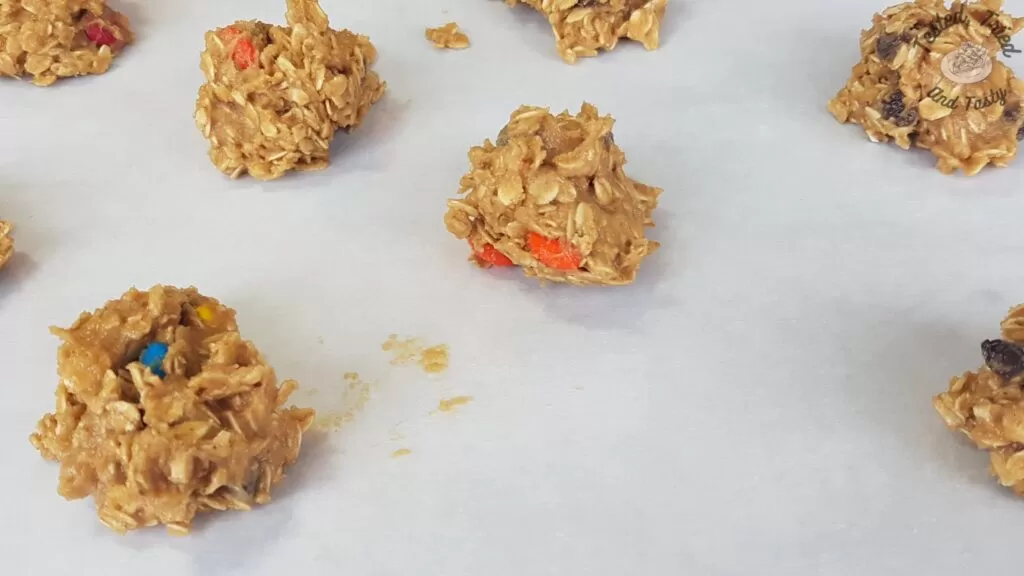 Dough balls for peanut butter, oatmeal, chocolate chip cookies on parchment paper.